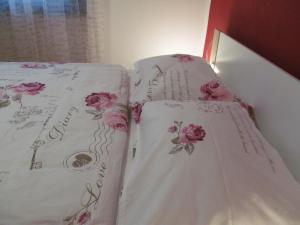 a bed with white sheets with pink flowers on it at Apartments ZVEZDICA*** with garden in Zambratija