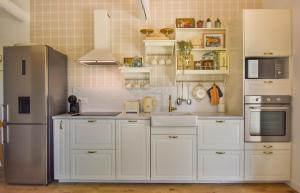 a kitchen with white cabinets and a stainless steel refrigerator at Cottage Sylvie à 25 minutes Cassis in Roquevaire