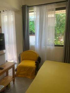 モンバサにあるImani’s homeのベッドルーム1室(窓の前に黄色い椅子付)