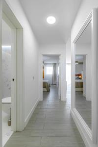 a white hallway with a mirror and a bedroom at 2-bed AMAZING OCEAN VIEW APARTMENT Costa Adeje in Adeje