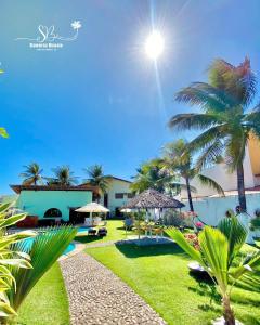 um pátio de resort com palmeiras e uma piscina em Pousada Sunrise Beach em Cumbuco