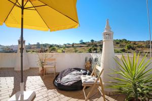 a patio with an umbrella and chairs and a lighthouse at Casa do Lavrador Furnazinhas in Odeleite
