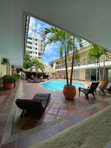 uma piscina com cadeiras e palmeiras num edifício em Najhomi Beach em Santa Marta