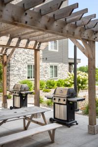 einem Picknicktisch und zwei Grills unter einer hölzernen Pergola in der Unterkunft Waterwalk Minneapolis Plymouth in Plymouth