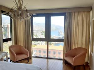 a bedroom with two chairs and a large window at One bedroom apartement with sea view shared pool and enclosed garden at Sao Martinho Funchal in Funchal