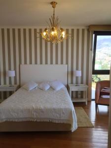a bedroom with a white bed and a chandelier at One bedroom apartement with sea view shared pool and enclosed garden at Sao Martinho Funchal in Funchal