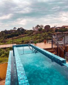 uma piscina azul com um deque de madeira em Pousada Jardim dos Elefantes em Catas Altas