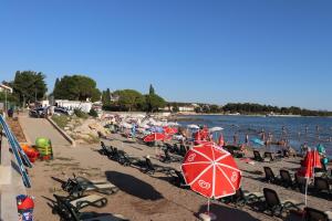 una playa con sombrillas y gente en la playa en Apartments ZVEZDICA*** with garden, en Zambratija