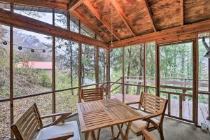 een afgeschermde veranda met een houten tafel en stoelen bij Peaceful Cottage with Mtn View Near ATV Trails! in Welch