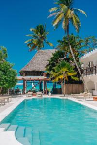 una piscina con palmeras y un cenador en Dhow Resort, en Jambiani
