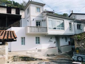a white house with a balcony on top of it at Amodiño do Camiño in Belesar