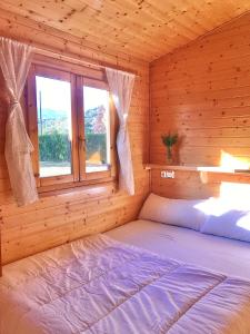 Ce lit se trouve dans une cabane en rondins dotée d'une fenêtre. dans l'établissement Camping Gran Sol, à Montferrer