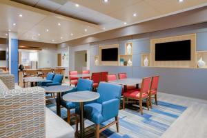un restaurante con mesas y sillas y TV de pantalla plana en Holiday Inn Express & Suites Ft. Washington - Philadelphia, an IHG Hotel, en Fort Washington