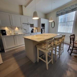 a kitchen with white cabinets and a large island with chairs at Chapter House YORK in York