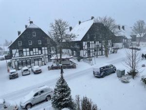 eine schneebedeckte Stadt mit Autos, die vor Gebäuden geparkt sind in der Unterkunft Haus Merian in Winterberg