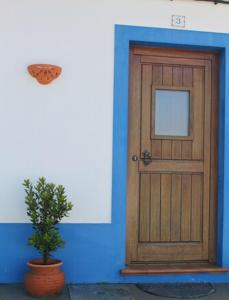 a blue building with a wooden door and a potted plant at Casa de Seixe in Odeceixe