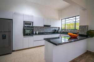 a kitchen with white cabinets and a black counter top at Casa El Roble paipa in Paipa