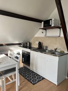 a kitchen with white cabinets and a sink and a table at Appartement coquet dans maison individuelle in Lisses +8 photos