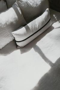 Una cama con sábanas blancas y almohadas. en La Masia Costa Brava, en Garrigás