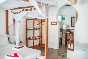 a bedroom with a bunk bed and a bathroom at Dhow Resort in Jambiani