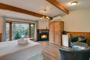a bedroom with a fireplace and a bed and chairs at Hôtel du Lac Lenore in Sainte-Adèle