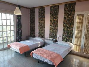 two beds in a room with floral wallpaper at Casa Rural Fayna in Granadilla de Abona