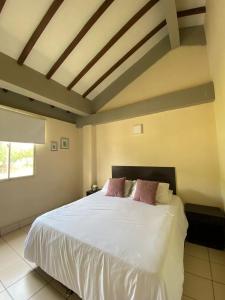 1 dormitorio con 1 cama con sábanas blancas y almohadas rosas en Najhomi Beach, en Santa Marta