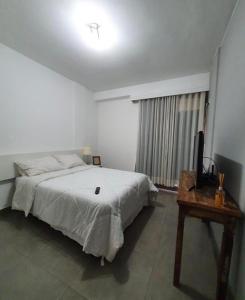 a bedroom with a bed and a television and a table at Apartamento aconchegante no Sudoeste in Brasilia