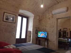 ein Schlafzimmer mit einem TV in einer Steinwand in der Unterkunft Casa Perosi in Noci