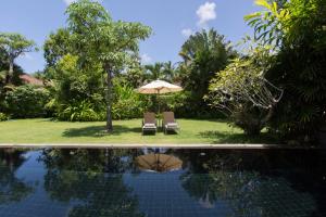 - Piscina con sombrilla, 2 sillas y mesa en Villa Koru Samui, en Mae Nam