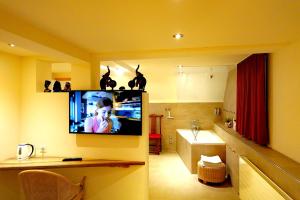 a room with a tv on the wall with a bathroom at Hotel JiuDing in Hochdorf