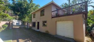 a house with a garage door and a balcony at The Court House- Ramsgate KZN in Ramsgate +11 photos