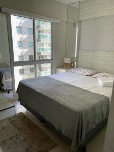 um quarto com uma cama grande e uma janela grande em Apartamento Confortável e Completo - JTR em Maceió