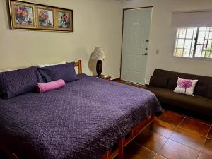 a bedroom with a purple bed and a couch at Jardín del Edén in Bajo Boquete