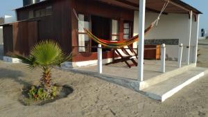 una casa con una hamaca frente a ella en la playa en Hotel Las Aldas, en Casma