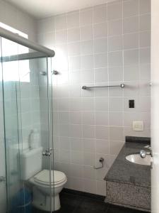 uma casa de banho com um WC e uma cabina de duche em vidro. em HOTEL ENSEADA BEIRA MAR no Guarujá