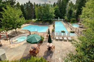 モントランブランにあるTremblant Les Eaux 227-1 by Escapades Tremblantのテーブルとパラソル付きのスイミングプールのオーバーヘッドビュー
