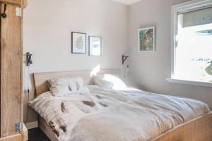 ein weißes Bett in einem Schlafzimmer mit einem Fenster in der Unterkunft Logies De Hooiberg in Lutjewinkel