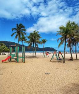 a group of playground equipment on a beach with palm trees at Lindo Apartamento Pé na Areia Canto do Forte in Solemar