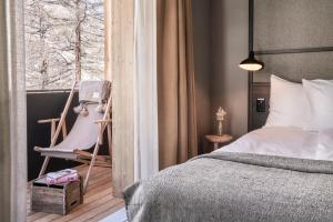 a bedroom with a bed and a chair and a window at Nomad by CERVO Mountain Resort in Zermatt