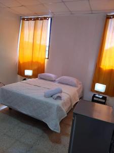 a bedroom with a bed with two lamps and a table at Hotel Colonial Blanco in Santo Domingo