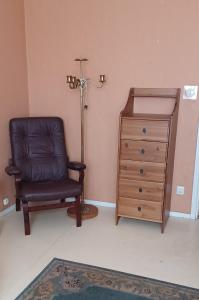 a room with a chair and a dresser and a lamp at Arthome Oxelösund in Oxelösund