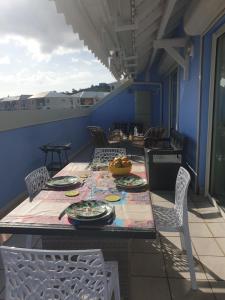 un tavolo e sedie su un balcone con tavolo e piatti di L'Arbre aux Papillons, Marina de Rivières-Sens a Gourbeyre