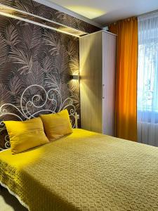 - une chambre avec un grand lit et des oreillers jaunes dans l'établissement Уютная комната-студия в центре Бишкека, à Bishkek