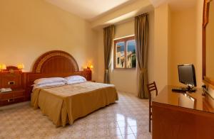 ソレントにあるHotel Villa Igeaのベッドとテレビが備わるホテルルームです。