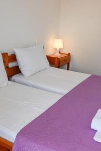 1 Schlafzimmer mit 2 Betten mit violetter Bettwäsche und einer Lampe in der Unterkunft Skiathos home with the best view in Skiathos-Stadt