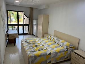 a bedroom with a bed with a yellow and gray blanket at Villa Kasa in Durrës