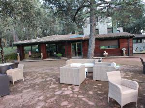 Hotel Rural Finca Liceo في Mijares: فناء مع كراسي الخوص والطاولات أمام المبنى