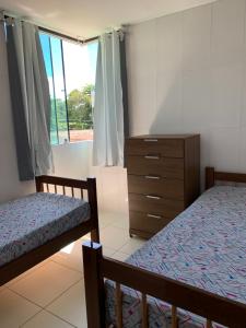 1 Schlafzimmer mit 2 Betten, einer Kommode und einem Fenster in der Unterkunft Maragogi Flat Residence in Maragogi