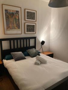 uma cama com lençóis brancos e almofadas num quarto em Goswell Central Apartment by DC London Rooms em Londres